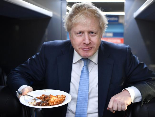 Britain's Prime Minister Boris Johnson eats a portion of pie on the campaign bus. Picture: AFP