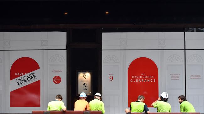 Construction workers sit outside the David Jones store in Sydney. Picture: AAP