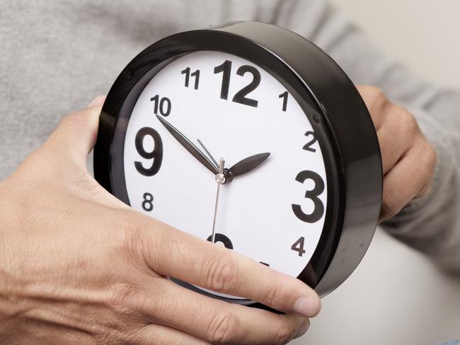 closeup of a young caucasian man adjusting the time of a clock