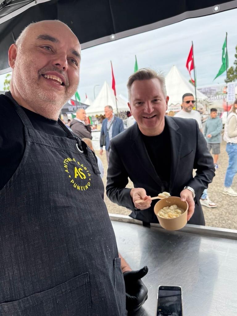 Chris Bowen purchasing the bowl of pasta from a festival stall.