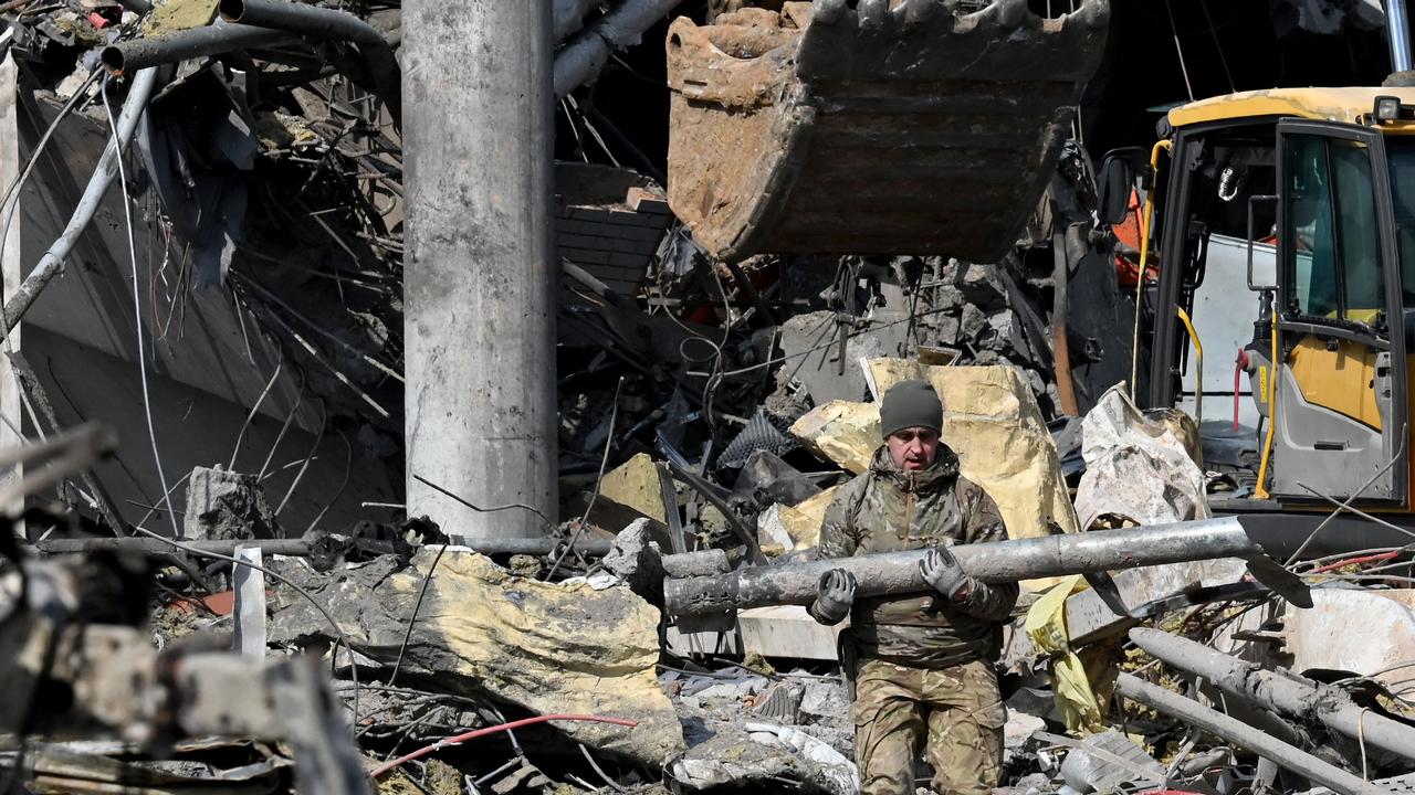 A Ukrainian serviceman carries a fragment of a rocket outside a building in Kyiv on March 24, 2022, after it was destroyed by Russian shelling. Picture: Sergei Supinsky/AFP