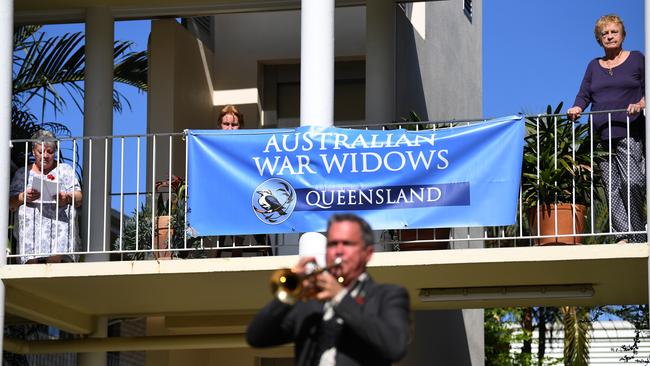 War widows watch musician Alastair Tomkins as he plays his trumpet during a small Anzac Day ceremony in Brisbane on Saturday.