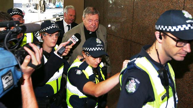 A line of police officers accompany the cardinal into court. Picture: Michael Dodge/Getty Images