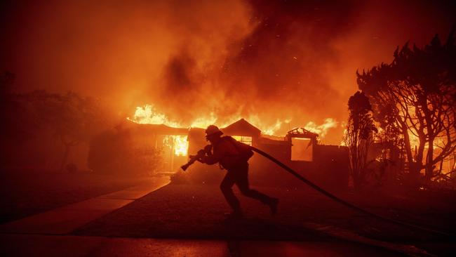 A firefighter battles the Palisades Fire as it burns a structure in the Pacific Palisades neighborhood of Los Angeles, Tuesday, Jan. 7, 2025. (AP Photo/Ethan Swope)