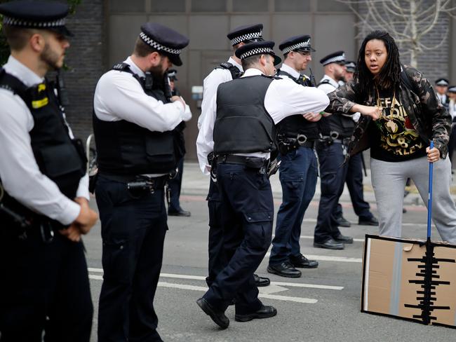 A protester bumps elbows with a police officer as demonstrators disperse after a march to the US Embassy during an anti-racism demonstration in London. Picture: Tolga Akmen