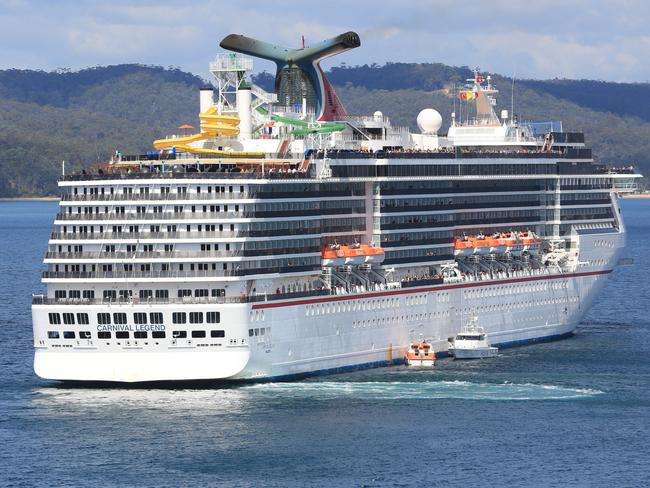 The Carnival Legend cruise ship sits in Eden harbour with police alongside.