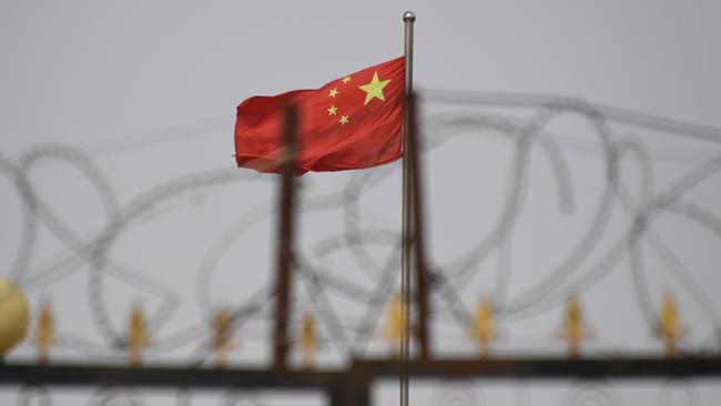 The Chinese flag behind razor wire at a housing compound in Yangisar in China's western Xinjiang region, home to most of the Uighur community. Picture: AFP