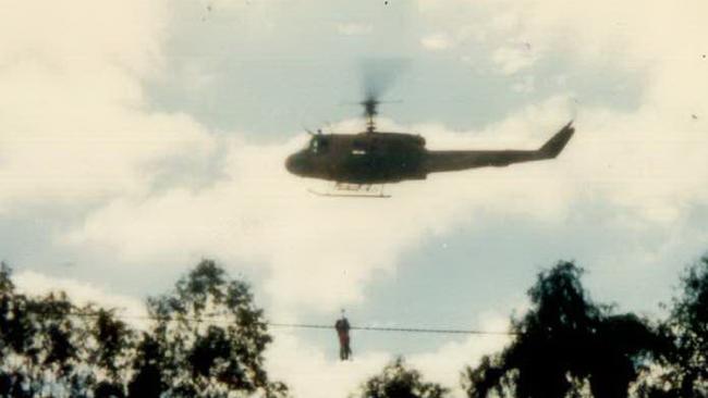 A couple cling to a helicopter's rescue lifeline. Charleville 1990 flood.