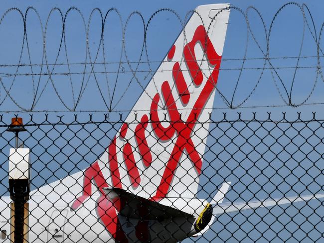 A grounded Virgin Australia aircraft is seen parked at Brisbane Airport in Brisbane, Friday, April 17, 2020. The Australian government has forced airline carriers to cut both their domestic and international flights in order to slow the spread of the coronavirus (COVID-19) disease. (AAP Image/Darren England) NO ARCHIVING