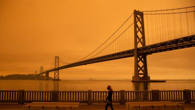 A woman walks along The Embarcadero under an orange smoke-filled sky in San Francisco. Picture: AFP