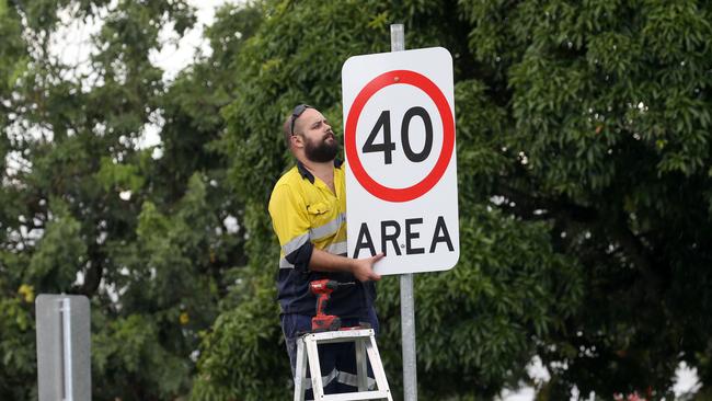 A worker installs a 40km/h speed limit sign. Picture: Anna Rogers