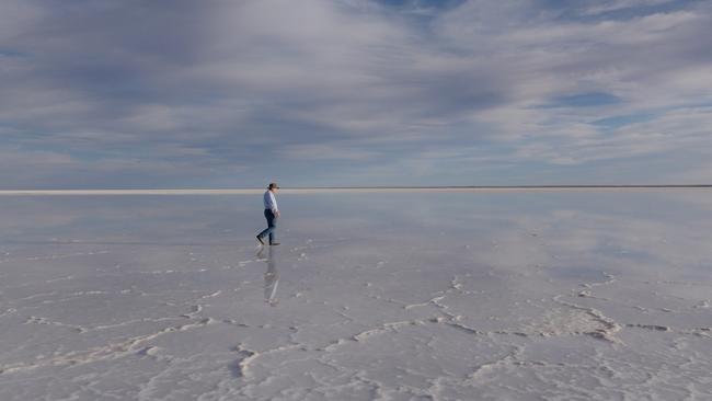 Charles Wooley walks out on to the southern section of Lake Eyre, where it is a blinding white, dry salt pan stretching to the horizon, during the filming of his program for Channel 7’s Spotlight called The Lake Picture: Arron Hage