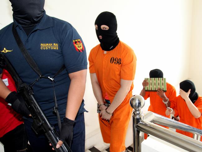 He and two other suspects sat on chairs behind officials at the conference, guarded by two officers also wearing balaclavas and carrying rifles. Picture: Lukman Bintoro