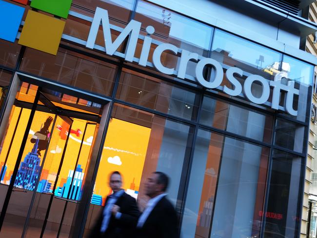 People pass by a Microsoft office in New York on October 6, 2015. Microsoft introduced a pair of big-screen smartphones and a laptop during an event in New York on Tuesday. The company unveiled the Surface Book, a laptop with 13.5-inch detachable touchscreen, the Surface Pro 4 tablet and the Lumia 950 and 950 XL smartphones, which feature displays measuring over 5 inches. The Surface devices launch later this month, while the Lumias arrive in November. AFP PHOTO/JEWEL SAMAD