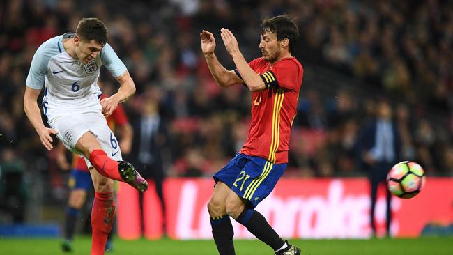 England's defender John Stones (L) clears the ball from the path of Spain's midfielder David Silva.