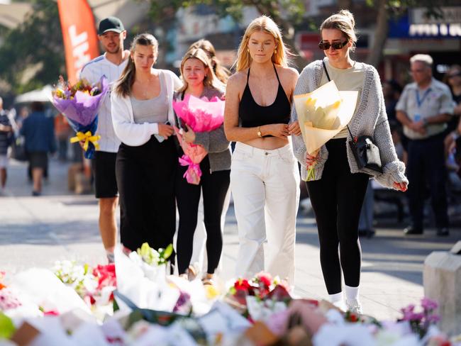 A group arrive to leave their flowers and pay their respects. Picture: David Swift