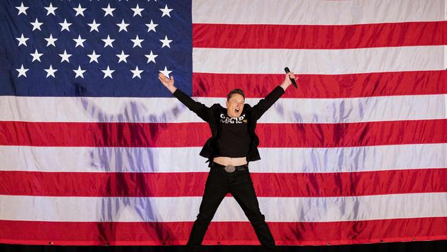 Elon Musk jumps on stage as he arrives to speak at a town hall event in support of Donald Trump. Picture: Ryan Collerd/AFP