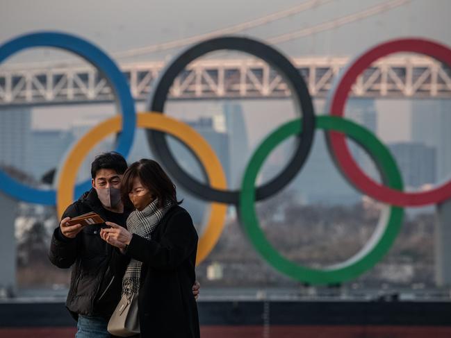 A couple in front of the Olympic Rings in Tokyo. Picture: Getty Images.