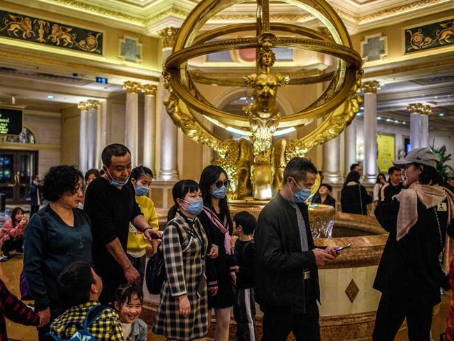 Visitors wear face masks as they walk inside the Venetian casino hotel resort in Macau at the beginning of the pandemic. Now the city has extended its closure of casinos. Picture: AFP