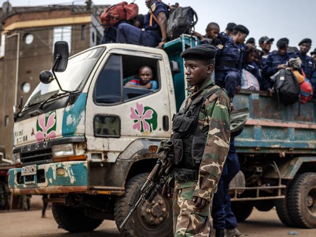 TOPSHOT - A member of the M23 movement looks on as Congolese police officers board trucks for redeployment following an enrollment of civilians, police officers, and former members of the Armed Forces of the Democratic Republic of Congo (FARDC) who allegedly decided to join the M23 movement voluntarily in Bukavu on February 22, 2025. Congolese President Felix Tshisekedi is on a quest for support as war in the east rages, but has so far returned empty-handed from trips abroad while anxiety mounts at home. Tshisekedi recently visited Angola and attended a security conference in Munich without making a clear diplomatic breakthrough, after Rwanda-backed M23 fighters seized control of two major eastern cities in the Democratic Republic of Congo. (Photo by Luis TATO / AFP)