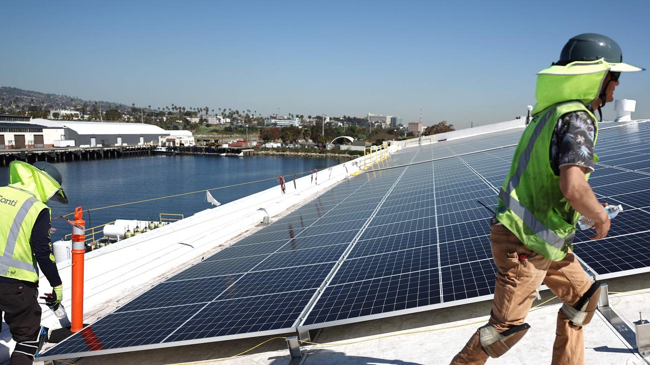 Workers install solar panels during the completion phase of a 4-acre solar rooftop atop AltaSea's research and development facility at the Port of Los Angeles for the biggest 'blue economy' tech hub. Picture: Getty Images