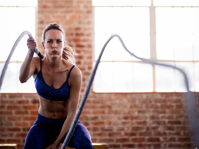 Girl doing fitness workout with ropes in gym