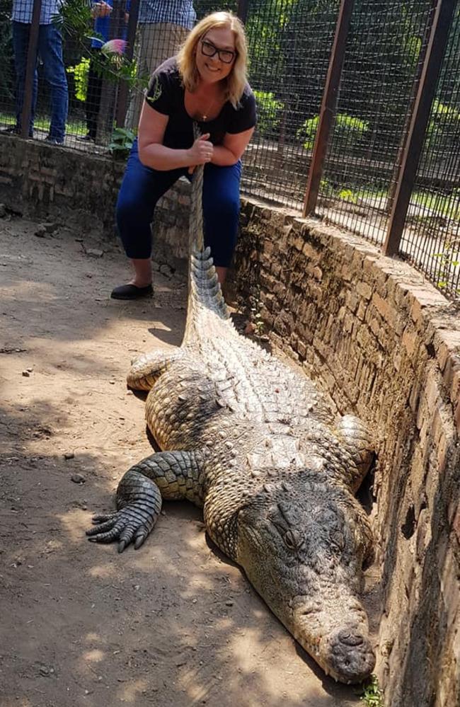 Linda holds the tail of a crocodile.