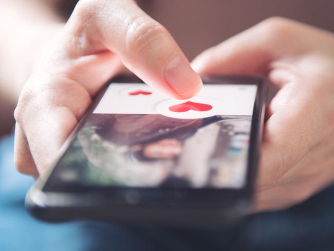 Finger of woman pushing heart icon on screen in mobile smartphone application. Online dating app, valentine's day concept.