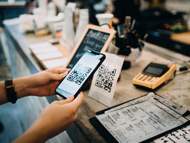 Customer scanning QR code, making a quick and easy contactless payment with her smartphone in a cafe