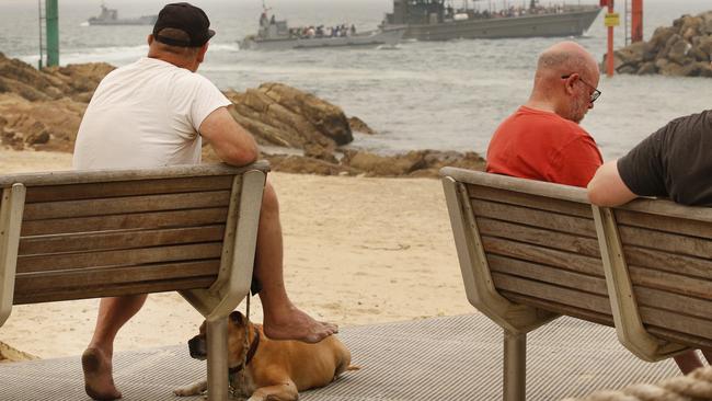 On shore, those who chose to stay in Mallacoota, watch the boats take evacuees to the waiting ships. Picture: David Caird