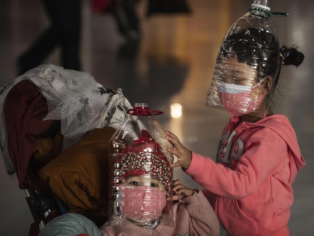 Children wearing makeshift homemade protection and protective masks while waiting to check-in to a flight at Beijing Capital Airport. Picture: Getty