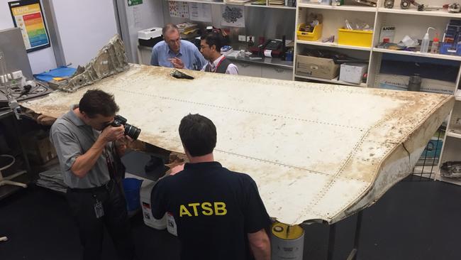 ‘Ongoing analysis’: Australian Transport Safety Bureau investigators examine the wing flap from MH370.