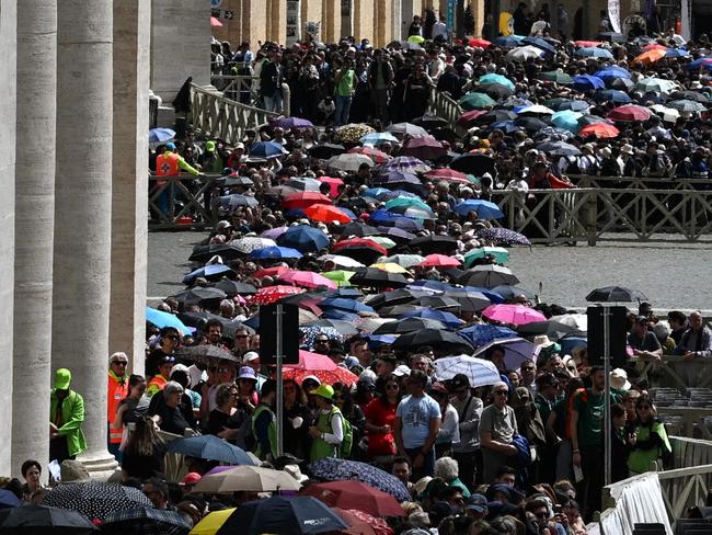People queue with umbrellas on St Peter's Square to access the basilica where the late Pope lies in state. Picture: AFP