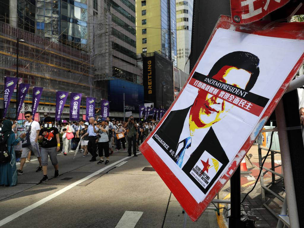 A poster of Chinese President Xi Jinping with his eyes blocked by words " Not my president" is seen as thousands of protesters march in Hong Kong. The Communist Party has an extensive network in place to report - and suppress - such protests. Picture: AP