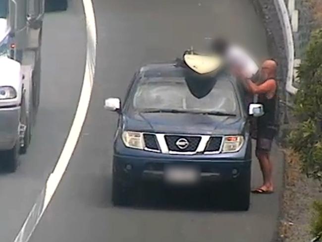 A driver lifts a child on to their vehicle beside a busy motorway. Picture: Transurban