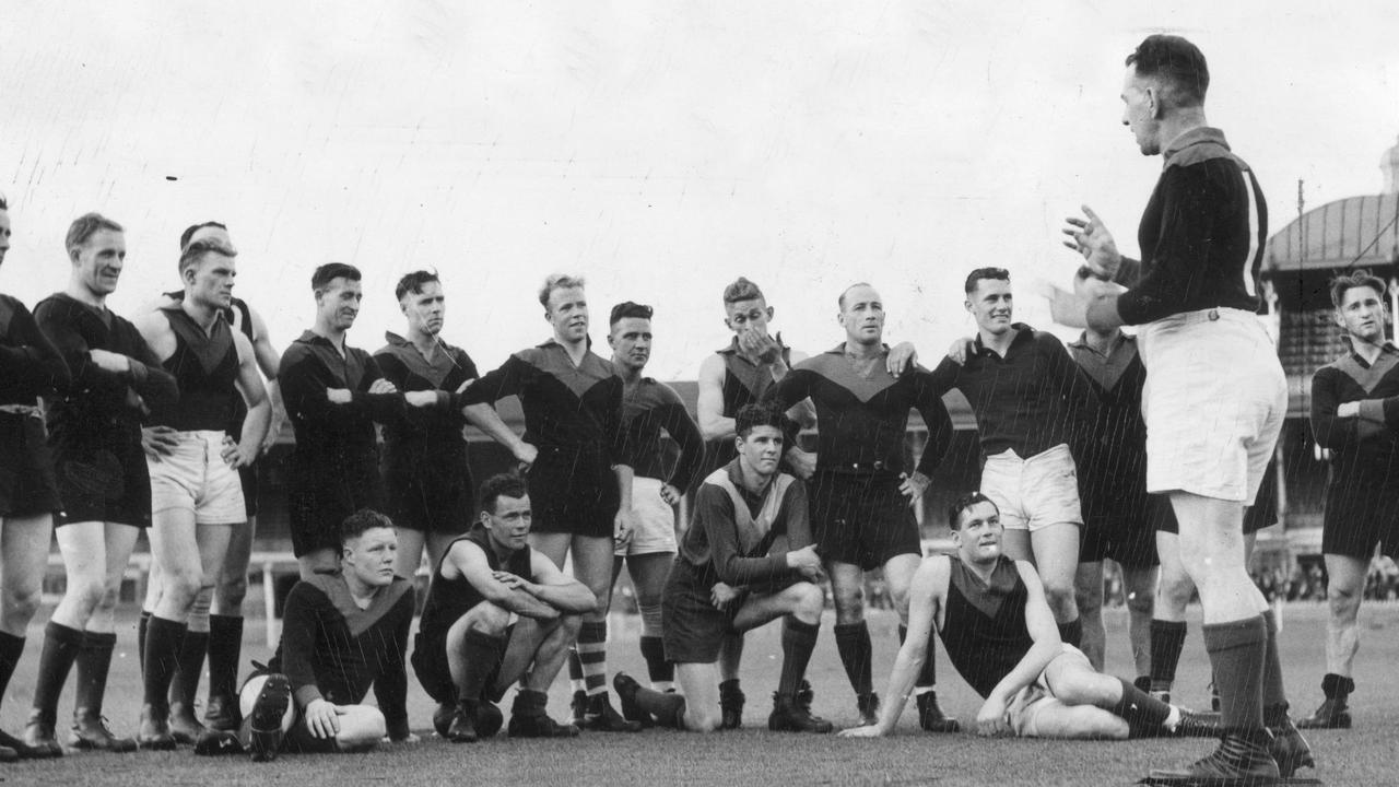 Melbourne coach Frank ‘Checker’ Hughes talks to the team in 1937 during a training session. Keith ‘Bluey’ Truscott is seated at left.