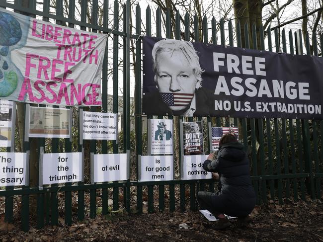 A supporter of Julian Assange tapes up protest messages near the court where the Australian is in the midst of an extradition hearing. Picture: AP