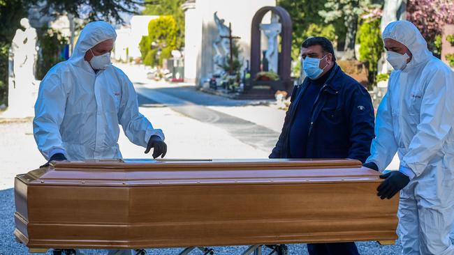 Undertakers wearing a face mask and overalls unload a coffin out of a hearse at the Monumental cemetery of Bergamo, Lombardy, as burials of people who died of the new coronavirus are being conducted at the rhythm of one every half-hour. Picture: AFP