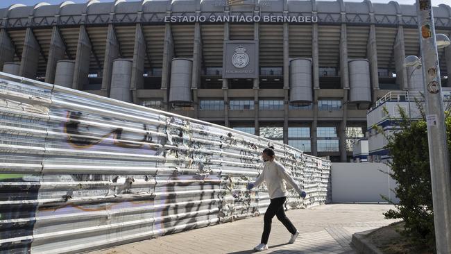 A woman wearing a protective mask walks past Real Madrid's Santiago Bernabeu stadium in Madrid