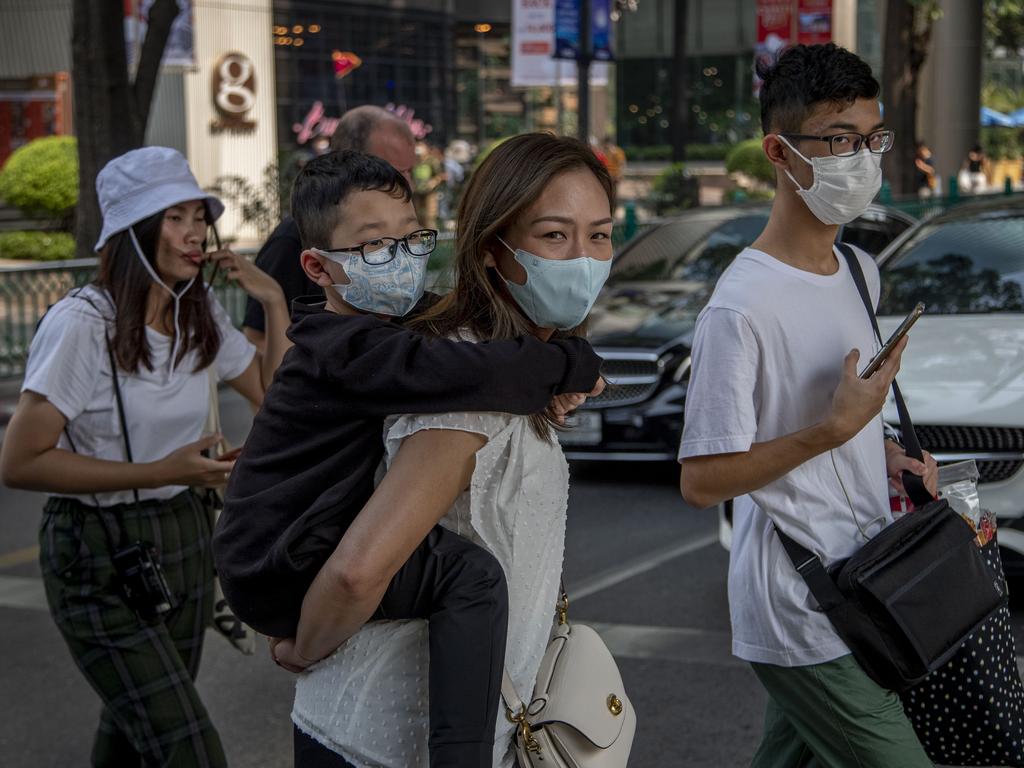 Demand for facemasks has surged, particularly in parts of Asia. Pictured, a Chinese family wearing face masks walk in a pedestrian crossing in Bangkok, Thailand. Picture: AP Photo/Gemunu Amarasinghe.