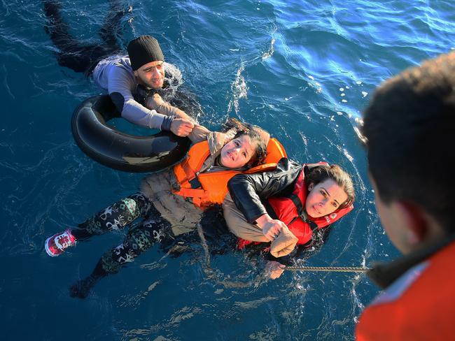 Getty Images Year in Focus 2016: Turkish Coast Guard personnel help refugees as they swim with buoys, after they toppled over a fishermen dinghy en route to Greece on January 22, 2016 in Didim district of Aydin, Turkey. 4 refugees body including 3 children pulled out of the water as Turkish coast guard personnel rescued 43 others. Photo by Emin Menguarslan/Anadolu Agency/Getty Images