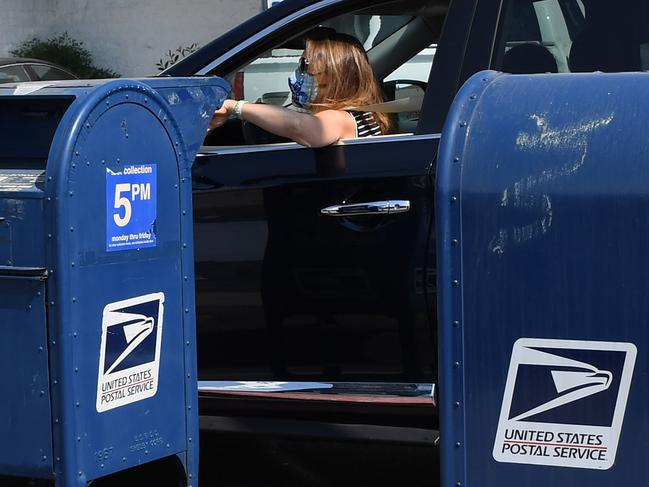 A person mails a letter at a mailbox outside a post office in Los Angeles, California, August 17, 2020. - The United States Postal Service is popularly known for delivering mail despite snow, rain or heat, but it faces a new foe in President Donald Trump. Ahead of the November 3 elections in which millions of voters are expected to cast ballots by mail due to the coronavirus, Trump has leveled an unprecedented attack at the USPS, opposing efforts to give the cash-strapped agency more money as part of a big new virus-related stimulus package, even as changes there have caused delays in mail delivery. (Photo by Robyn Beck / AFP)