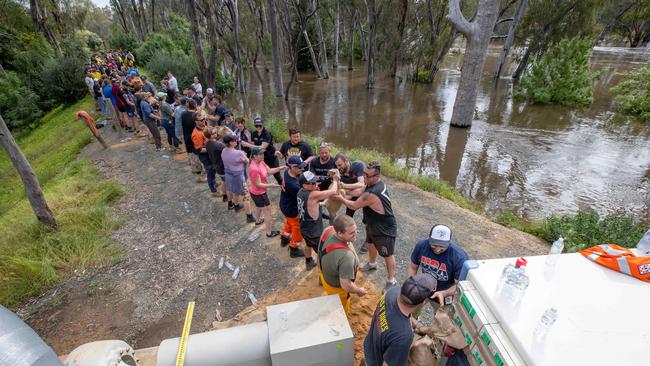 Dozens of locals band together to build a higher wall. Picture: Jason Edwards