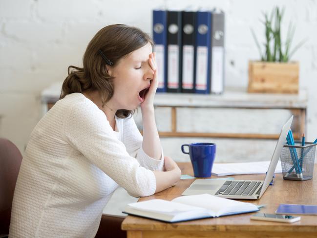 Portrait of young woman sitting at table in front of laptop, sleepy, tired, overworked, lazy to work. Attractive business woman yawning in home office relaxing or bored after work on laptop computer