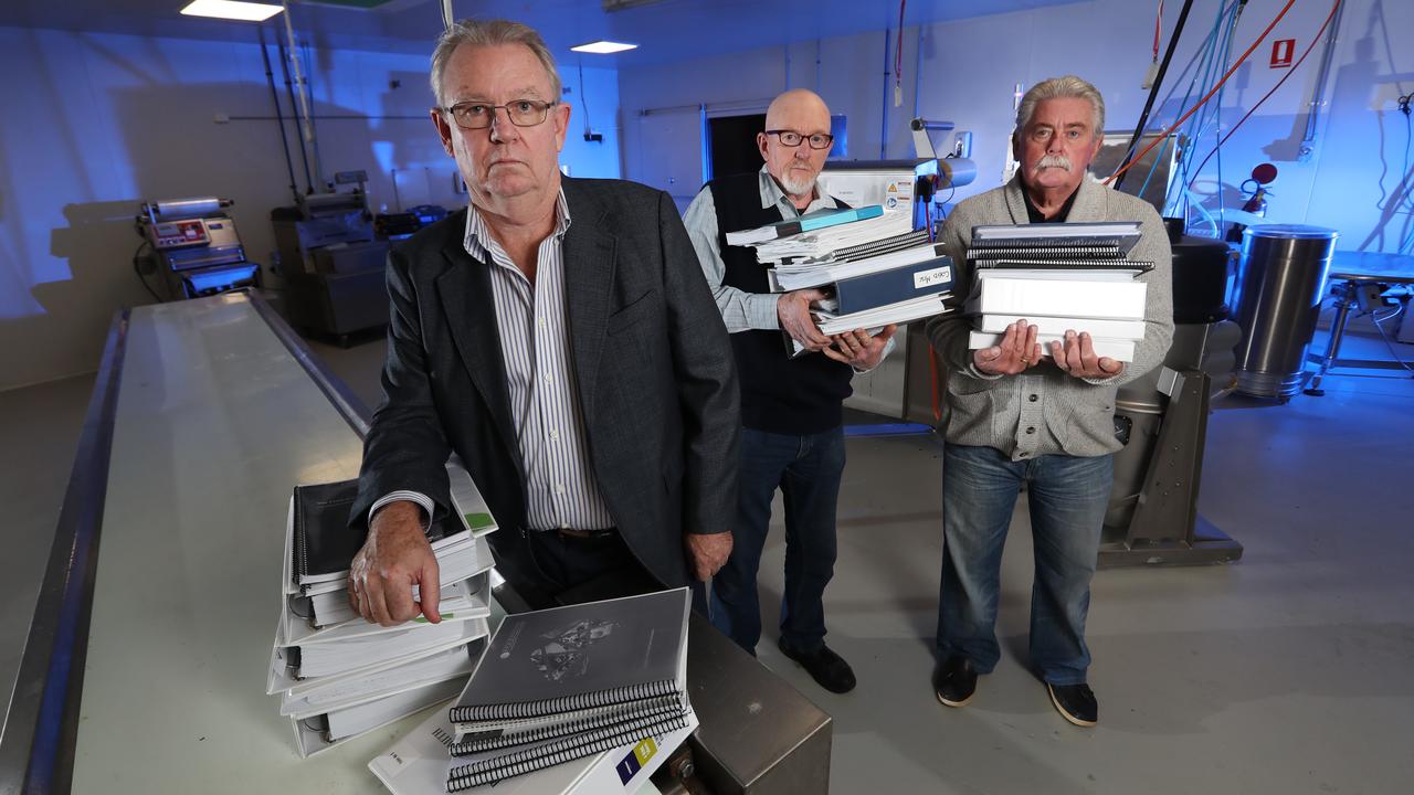 The boss of I Cook Foods, Ian Cook, with retired Detective Sergeant Paul Brady and retired Detective Inspector Rod Porter and the mountain of evidence submitted to Victoria Police. Picture: Alex Coppel.