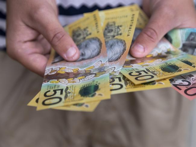 Male person holding some Australian currency. This visual concept evokes ideas around saving money, paying for expenses and investments.