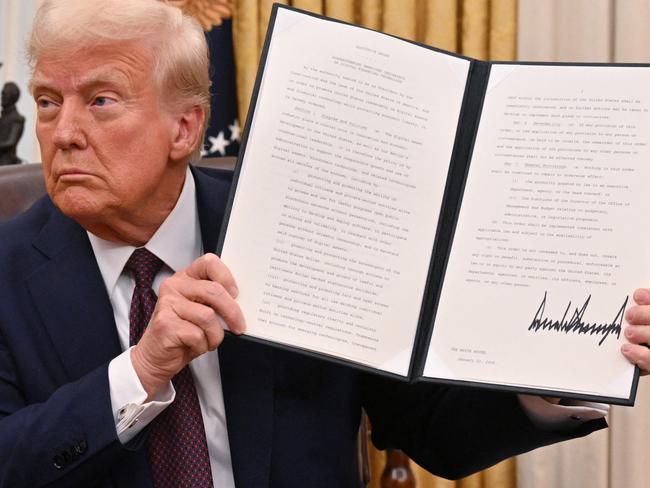 Mr Trump holds up one of his executive orders (not the DEI one) for the cameras in the Oval Office. Picture: Roberto Schmidt/AFP