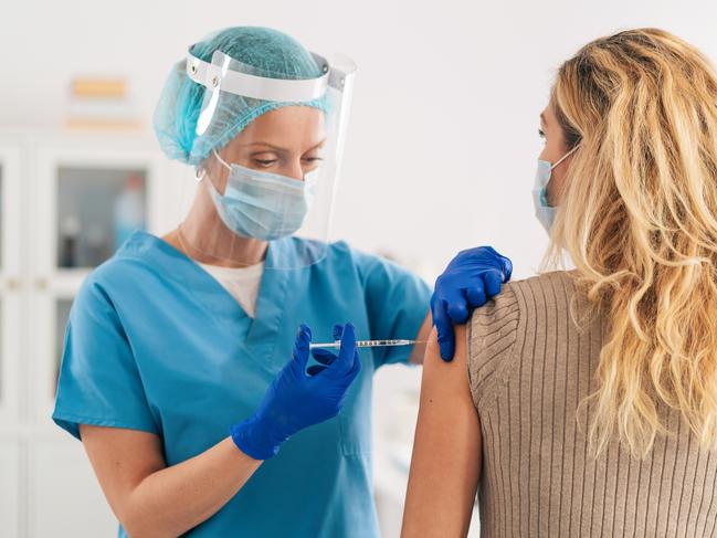 Doctor wearing protective work wear injecting vaccine into patient's arm