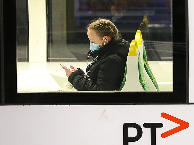Melbourne's CBD is very quiet for a Friday night as the city experiences a spike in coronavirus cases and more than 30 suburbs are forced into lockdown. A woman wears a mask on a tram in Swanston Street. Picture : Ian Currie
