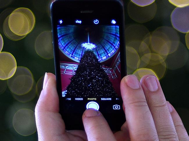 A man is seen taking photographs on a smartphone of the Christmas tree at the Queen Victoria Building in Sydney, Saturday, Dec. 3, 2016. (AAP Image/Dan Himbrechts) NO ARCHIVING